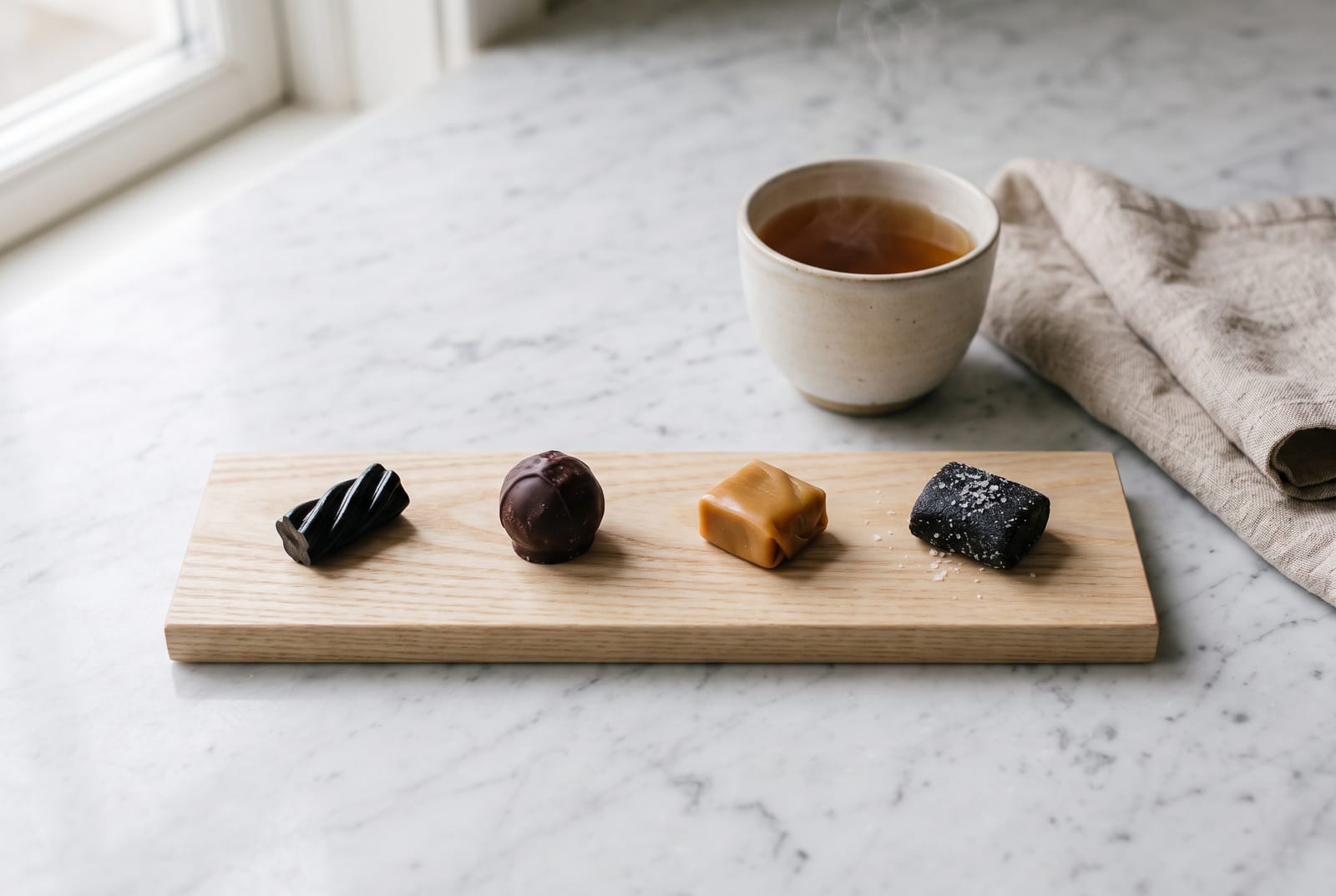 Four liquorice varieties arranged in tasting order on a timber board
